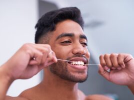 Shot of a handsome young man flossing his teeth in the bathroom at home